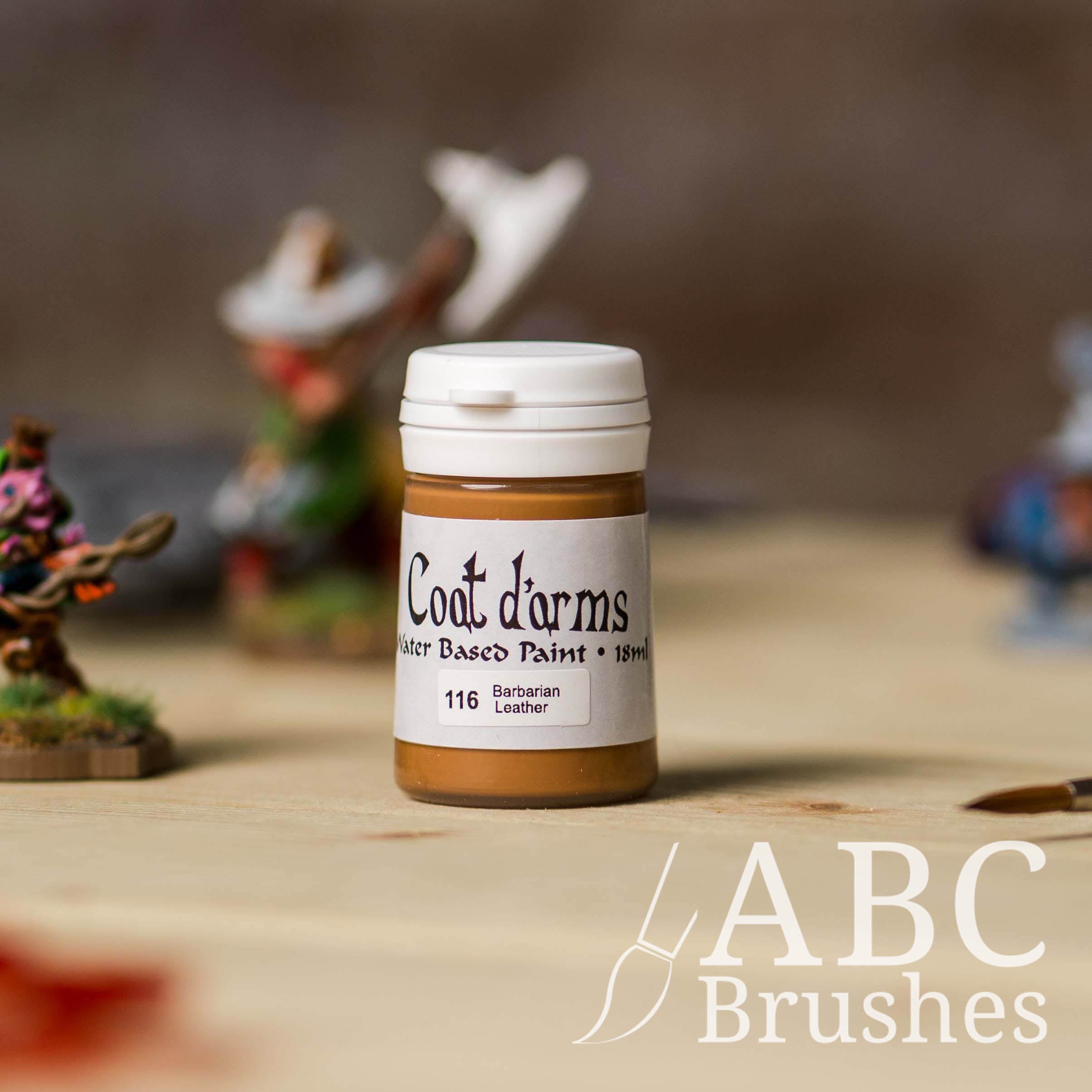 Bottle of Coat d'Arms acrylic paint in the colour Barbarian Leather, with various wargaming models and an abc paintbrush in the background, on a wooden surface.