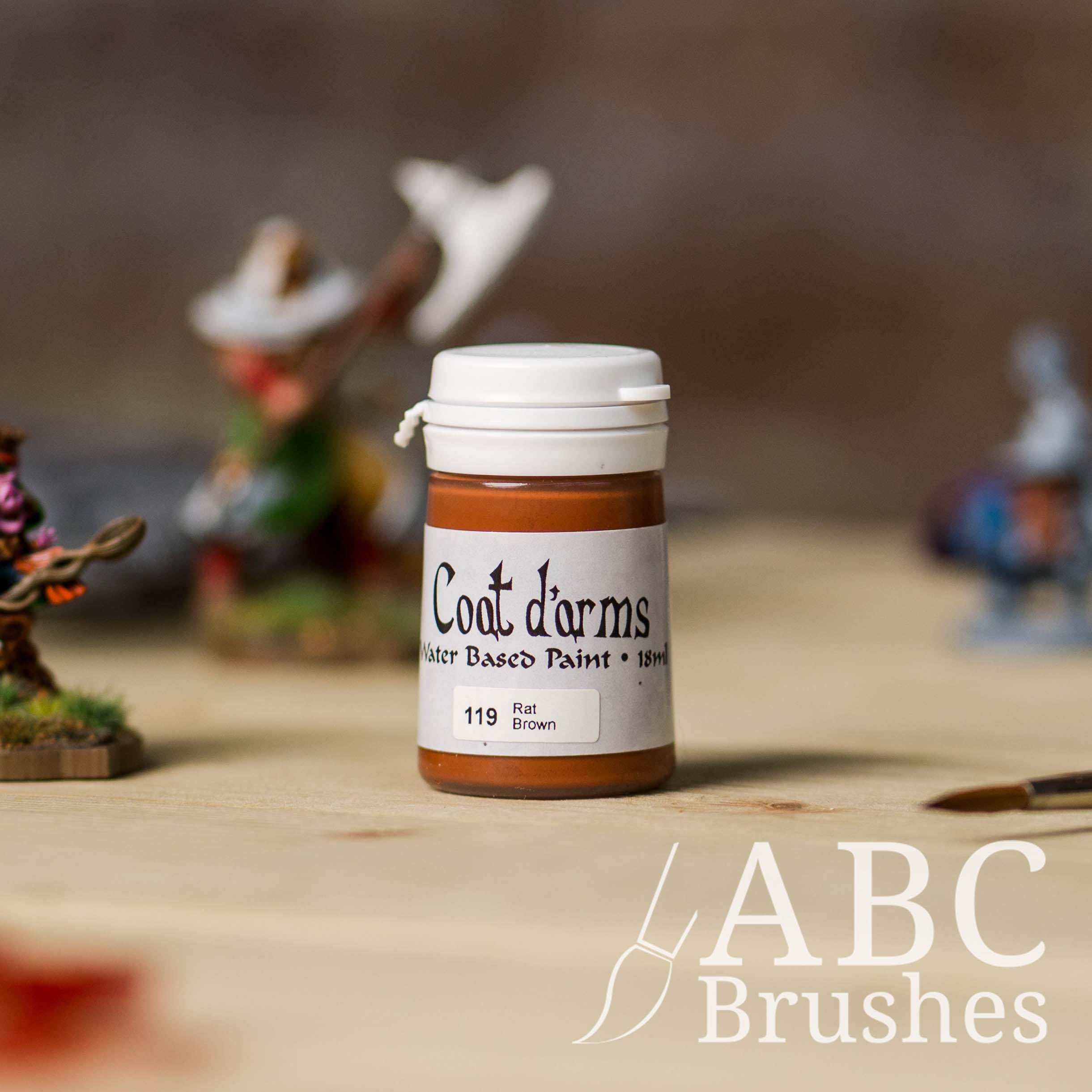 Bottle of Coat d'Arms acrylic paint in the colour Rat Brown, with various wargaming models and an abc paintbrush in the background, on a wooden surface.