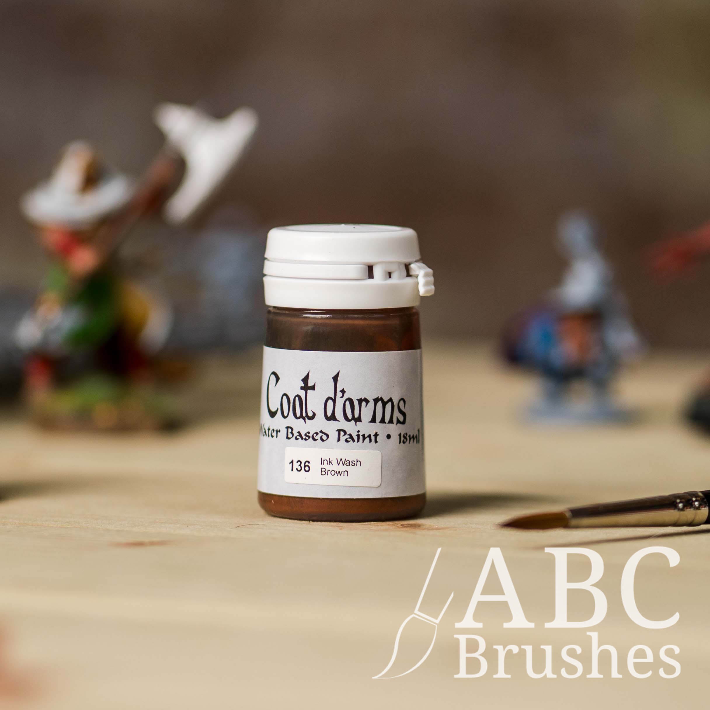 Bottle of Coat d'Arms ink wash in the colour Brown, with various wargaming models and an abc paintbrush in the background, on a wooden surface.