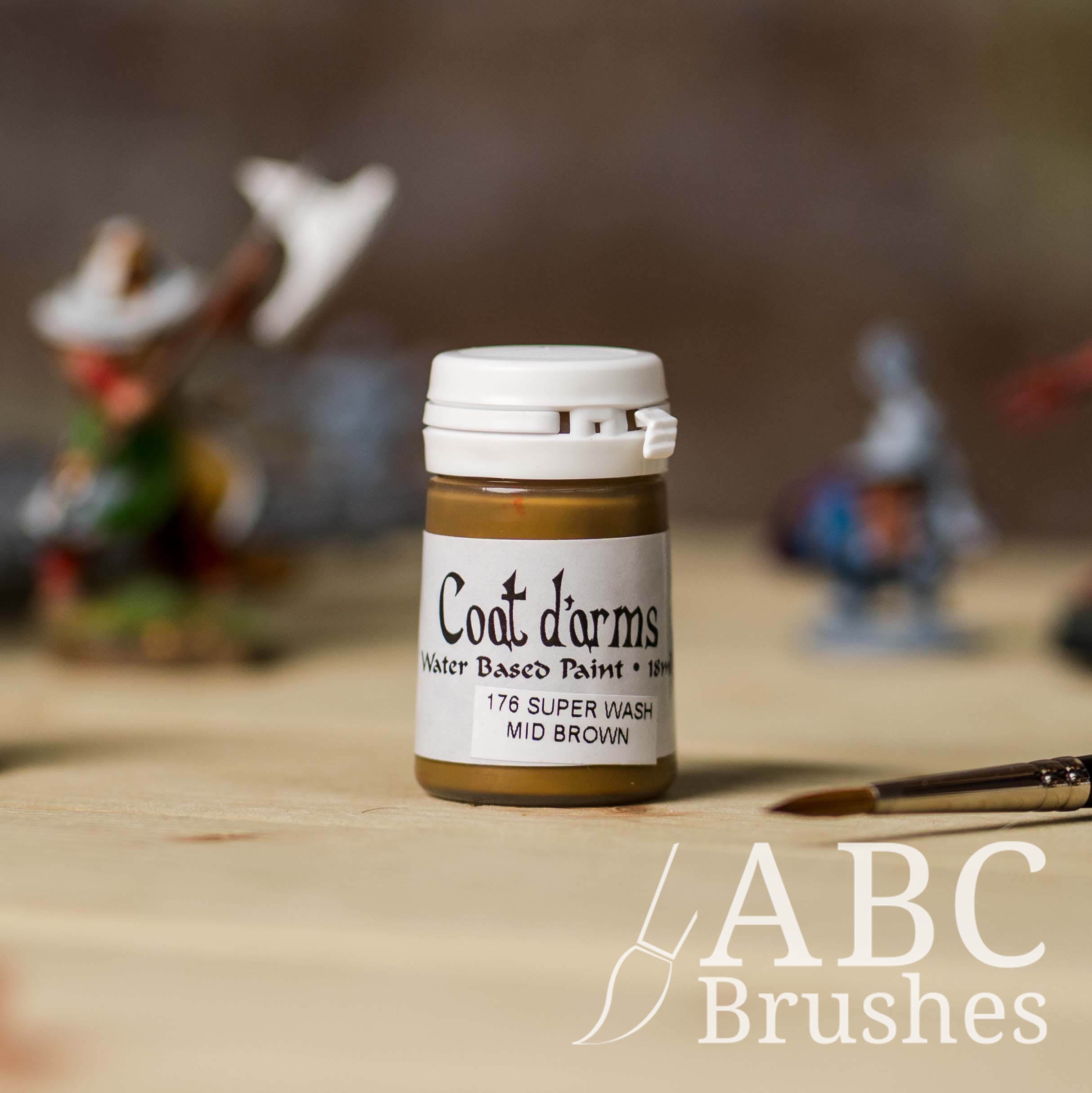 Bottle of Coat d'Arms Super Wash paint in the colour Mid Brown, with various wargaming models and an abc paintbrush in the background, on a wooden surface.