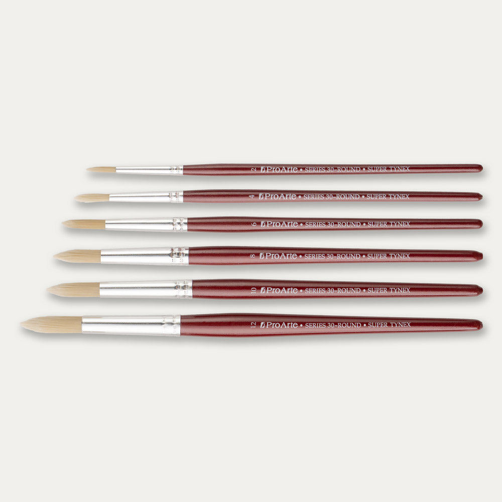 Six Pro Arte Round Dry brushes arranged in size order, laid out sideways on a white background.