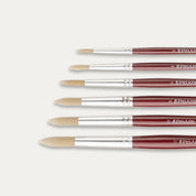 Closeup of the tips of Six Pro Arte Round Dry brushes arranged in size order, laid out sideways on a white background.