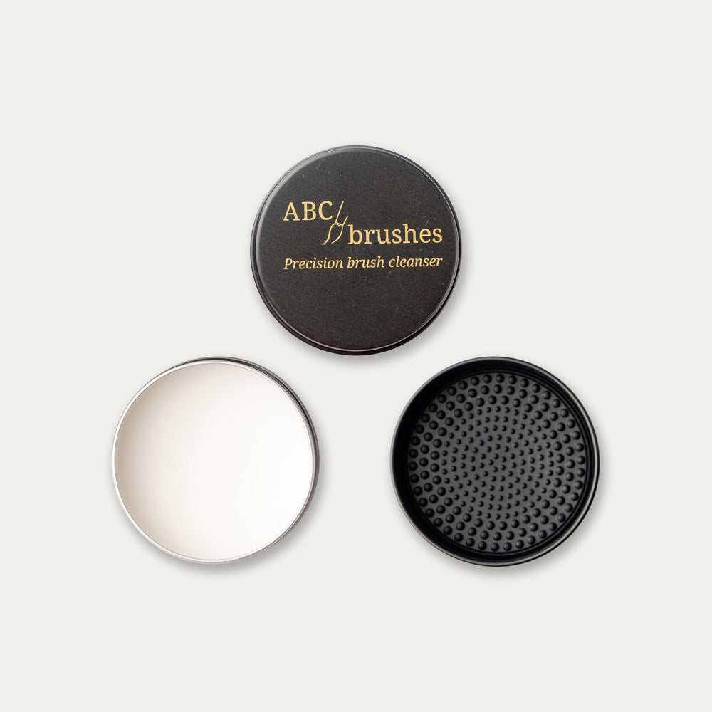 ABC brushes brush soap, lid, open product and textured lid arranged in a triangle on a white background. 