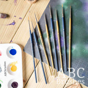 ABC Brushes All Media Micro Detail Synthetic brush range laid out on a paint covered cutting mat and next to a paint palette.
