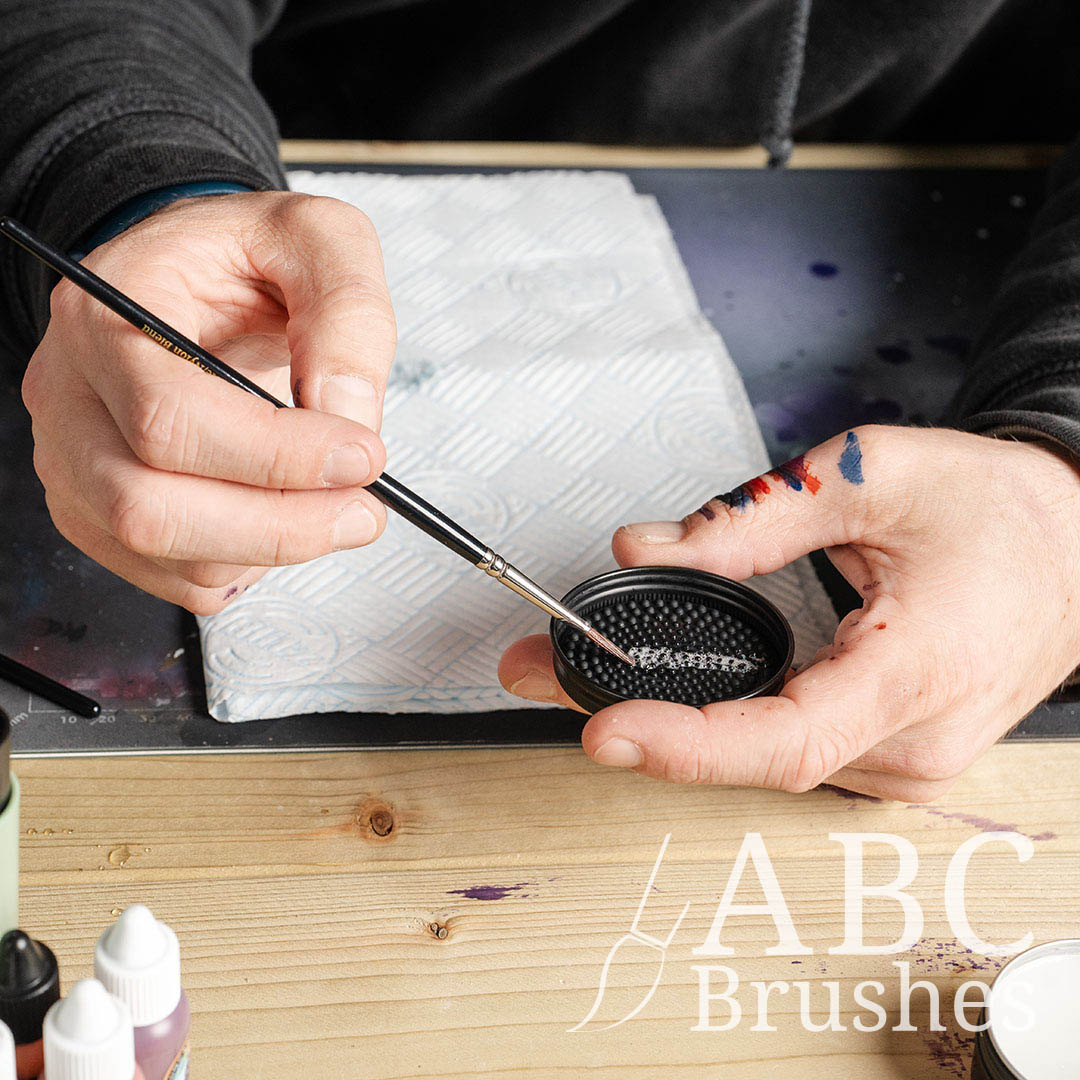 Someone cleaning a paintbrush with the textured lid of ABC Brushes brush cleaner.