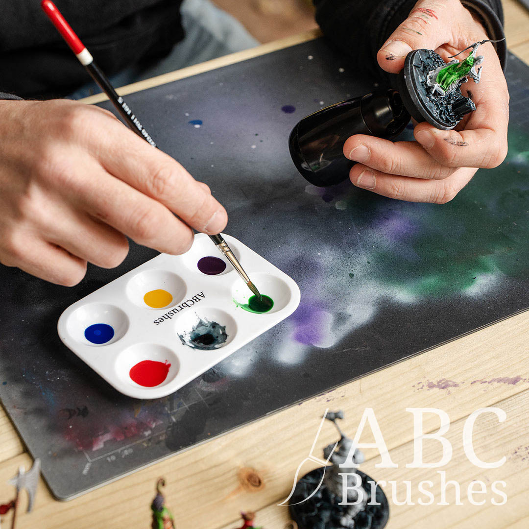 Person picking up green paint from an ABC Brushes palette with a Pro Arte Phalanx round paint brush to paint a archer mini. 
