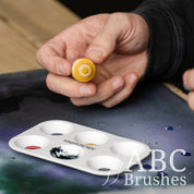 Pouring yellow acrylic paint into an ABC Brushes paint palette.
