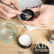 Someone cleaning a paintbrush with the textured lid of ABC Brushes brush cleaner.