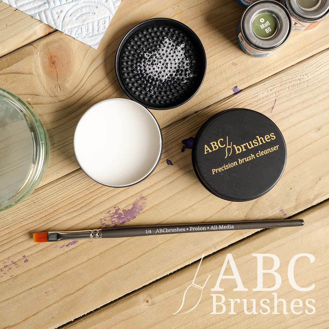 ABC Brushes brush soap, lid, open product and textured lid, with a ABC Brushes Prolon paint brush and other painting supplies around it. 