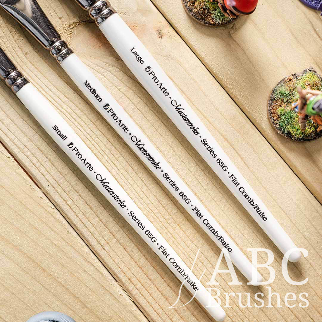Close-up of the handles of the Pro Arte Comb Paint Brush set on a wooden surface.