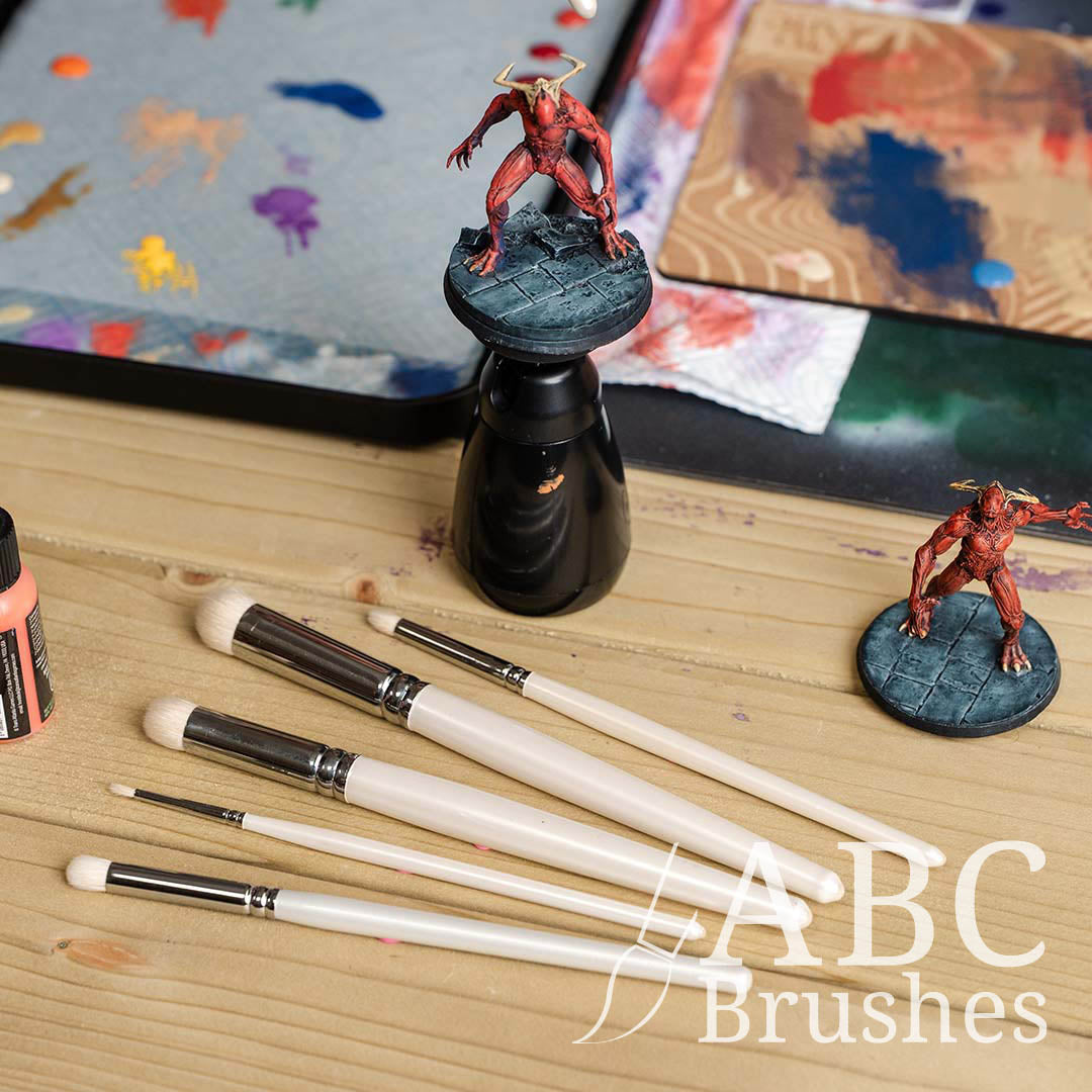 ABC Brushes Rounded Dry brush set next to a mini on a painting handle and various palettes. 