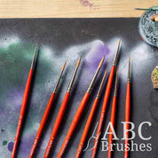 Close-up of the brush tips of the ABC Brushes Spearhead paint brush set laid out on a paint covered cutting mat.
