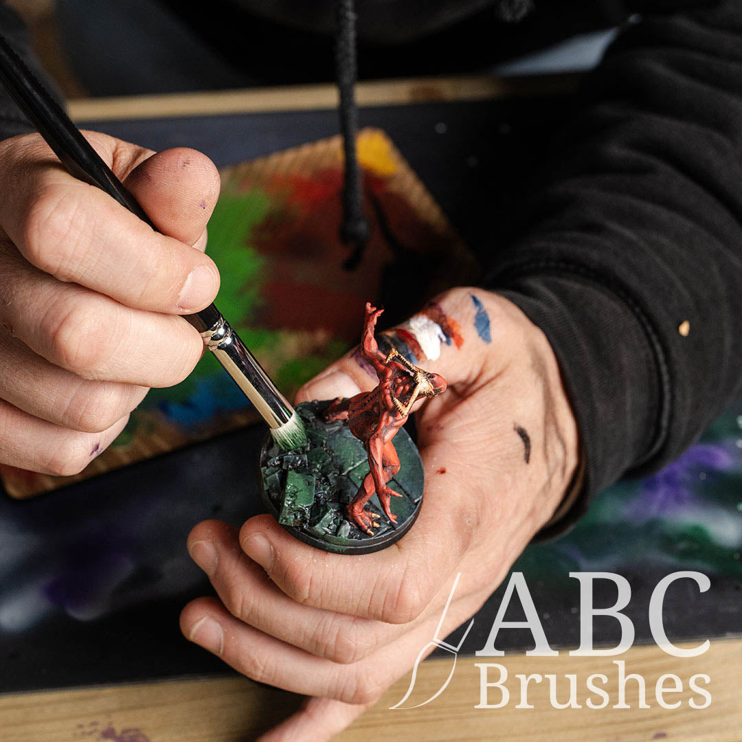 Applying moss weathering to a red demon-like mini with an Army Painter dry brush. 