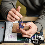 Applying purple paint to a mini using an Army Painter Dry Brush. 