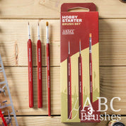 The Army Painter Hobby Starter brush set, next to the packaging on a wooden background.