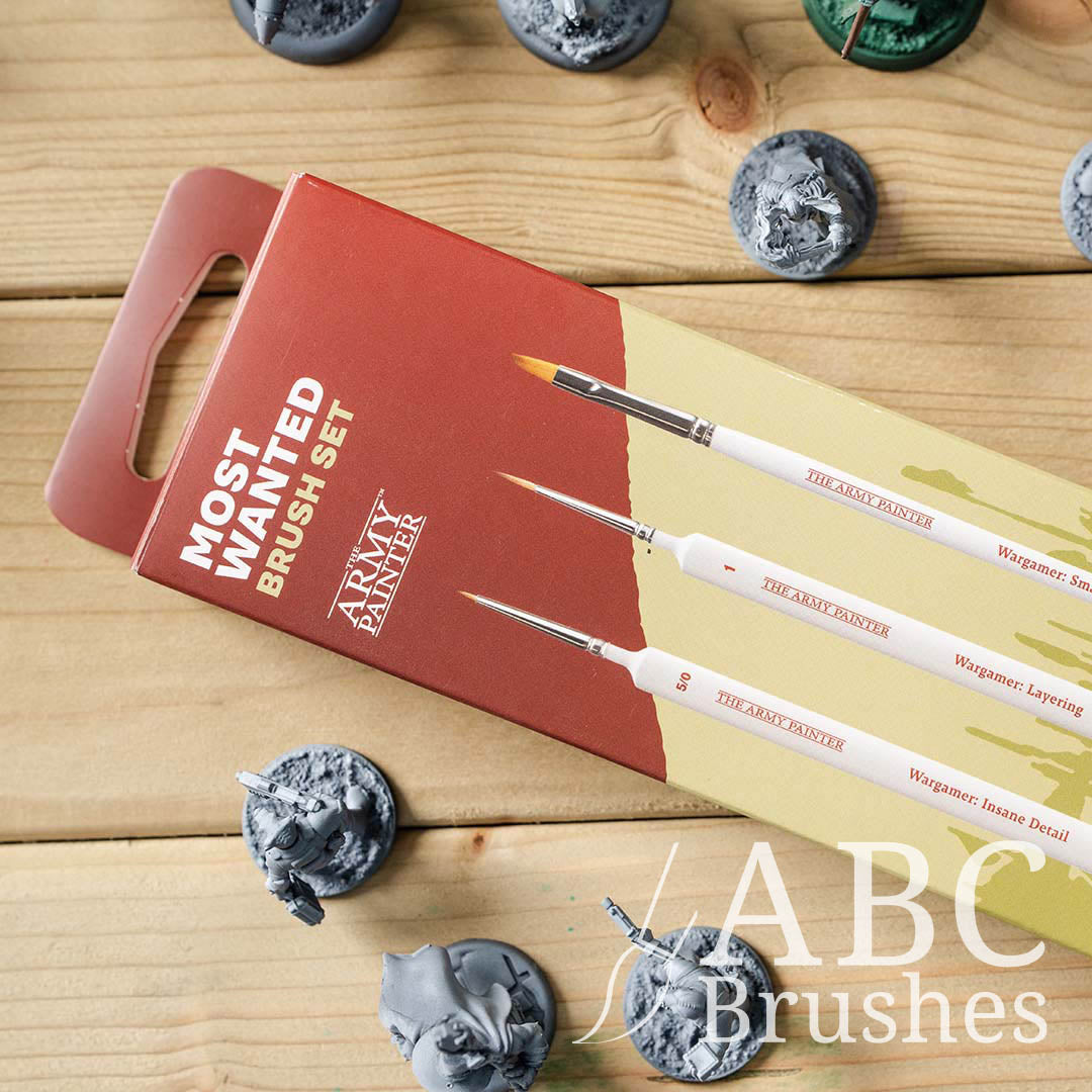The Army Painters Most Wanted brush set packaging on a wooden background, next to various miniature figures. 