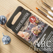 Packaging for the Army Painters Most Wanted brush set on a wooden background. 