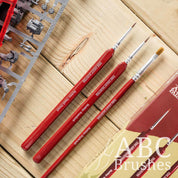 The Army Painter Hobby Starter brush set, laid out diagonally and next to the packaging and some sprues on a wooden background.