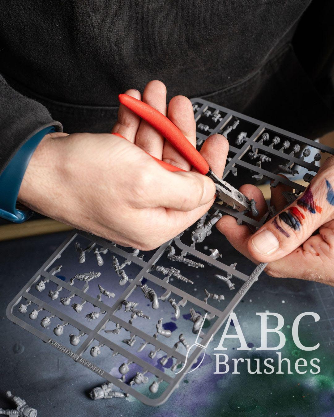 Cutting model pieces out of a sprue with a red plastic cutter. 