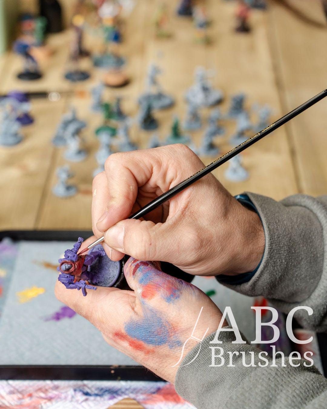 Painting a basecoat onto a mini in red paint, with a ABC Round Brush. 