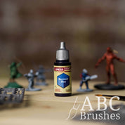 Bottle of the Army Painters Speedpaint in the colour Beowulf Blue, with wargaming models and an ABC paintbrush in the background, on a wooden surface.