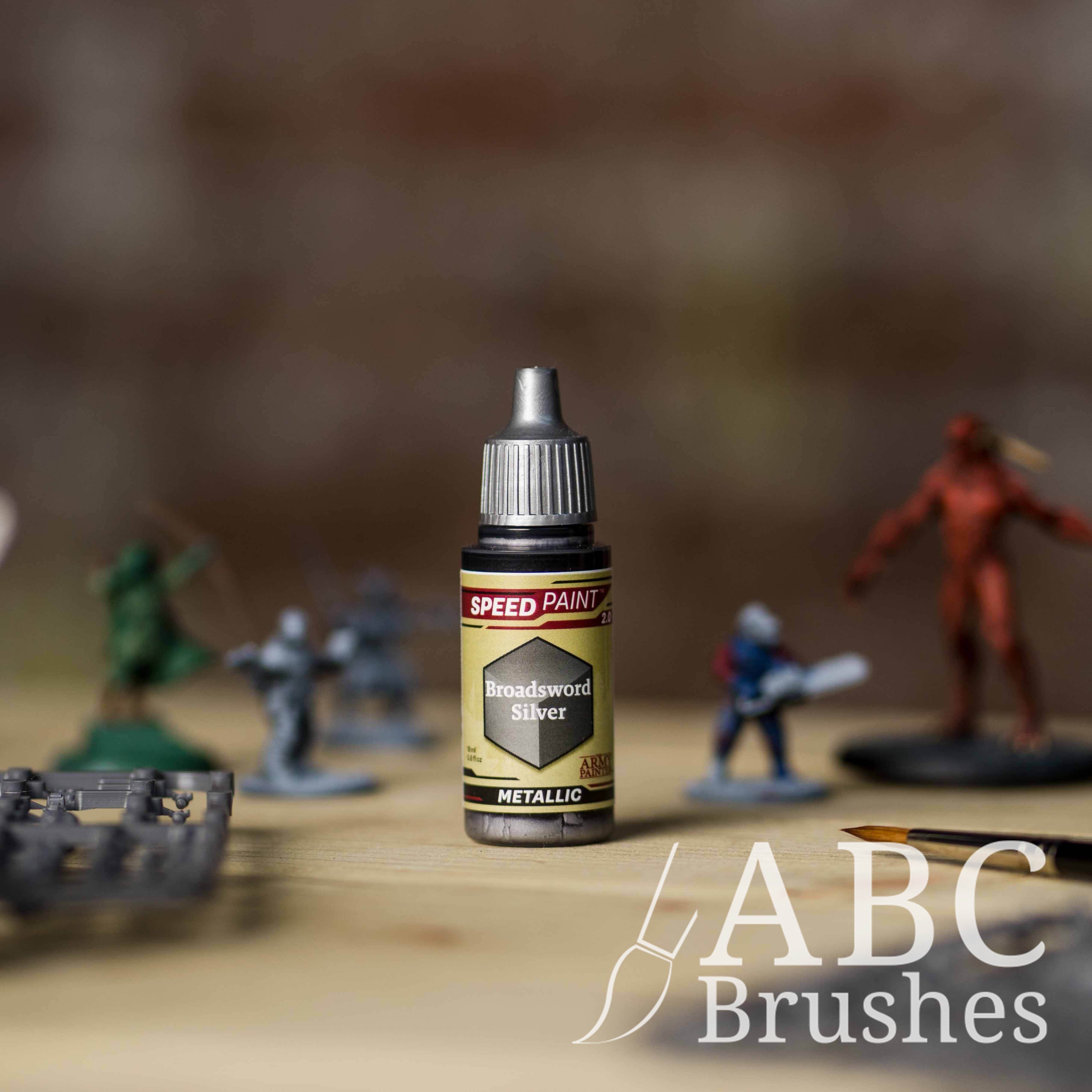 Bottle of the Army Painters Metallic Speedpaint in the colour Broadsword Silver, with wargaming models and an ABC paintbrush in the background, on a wooden surface.