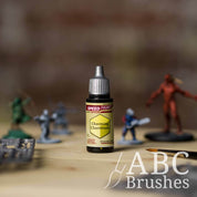 Bottle of the Army Painters Speedpaint in the colour Charming Chartreuse, with wargaming models and an ABC paintbrush in the background, on a wooden surface.
