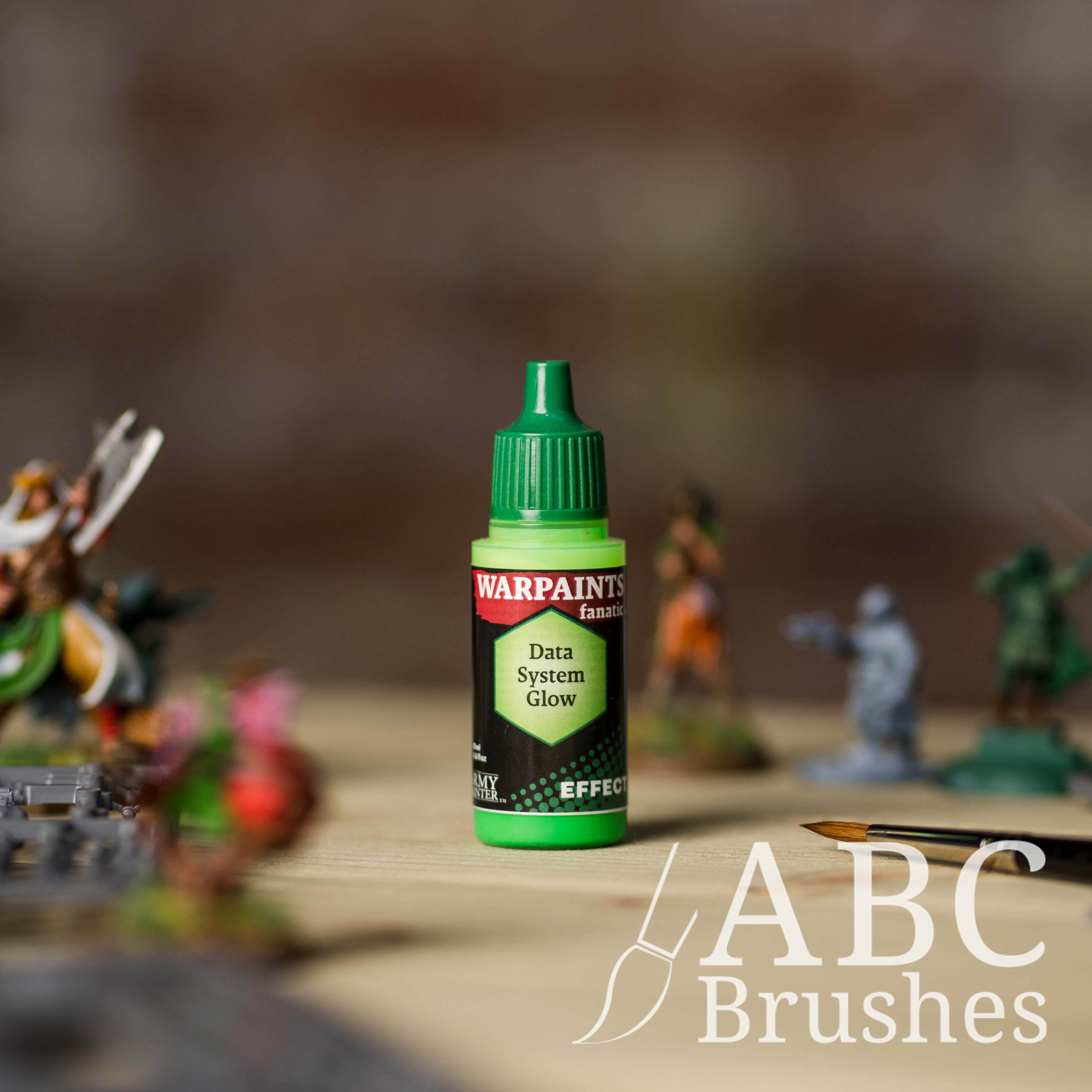 Bottle of the Army Painter Fanatics Effects in the colour Data System Glow with various wargaming models and an ABC paintbrush in the background, on a wooden surface.