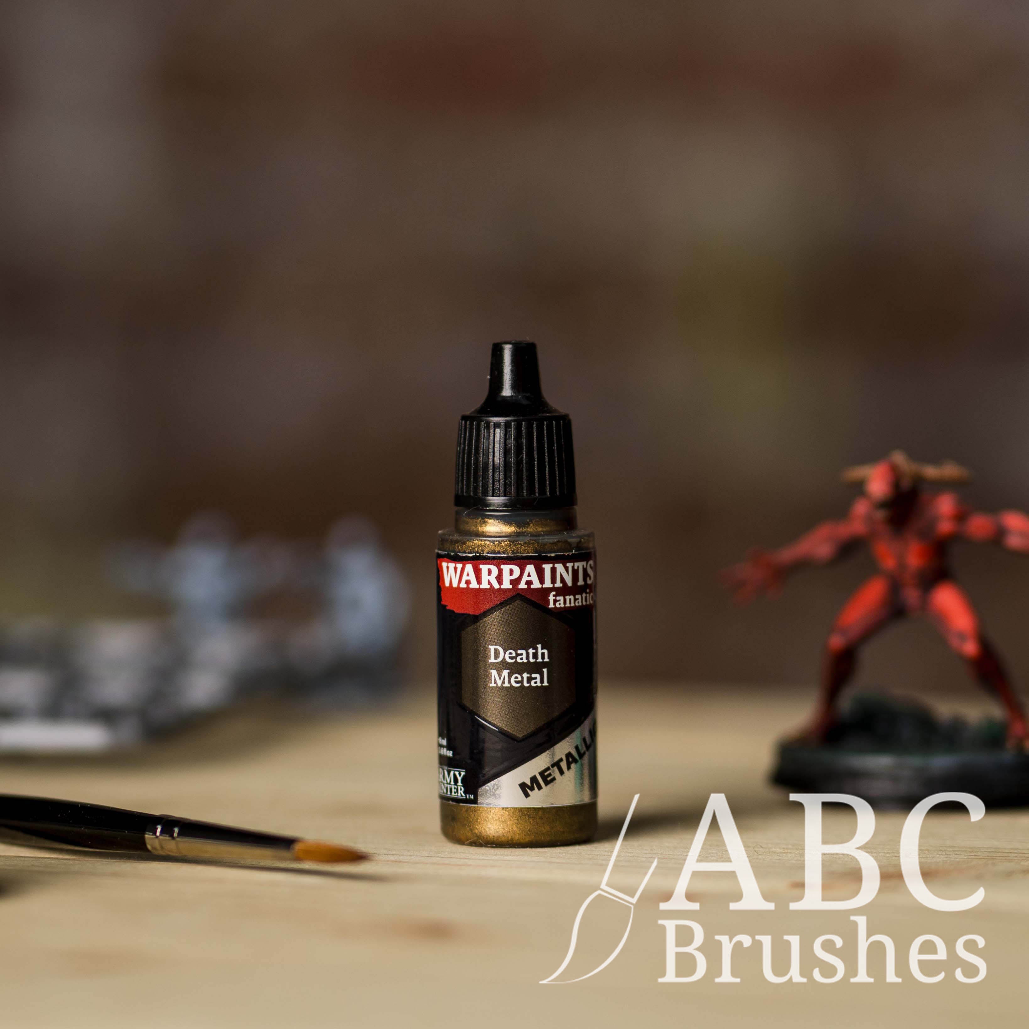Bottle of the Army Painter Fanatics Metallic paint in the colour Death Metal with various wargaming models and an ABC paintbrush in the background, on a wooden surface.