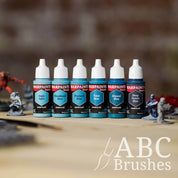 Army Painter Fanatics Deep Green Blues Triad on a wooden surface. There are wargaming models and an ABC paint brush next to them.