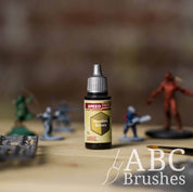 Bottle of the Army Painters Speedpaint in the colour Desolate Brown, with wargaming models and an ABC paintbrush in the background, on a wooden surface.
