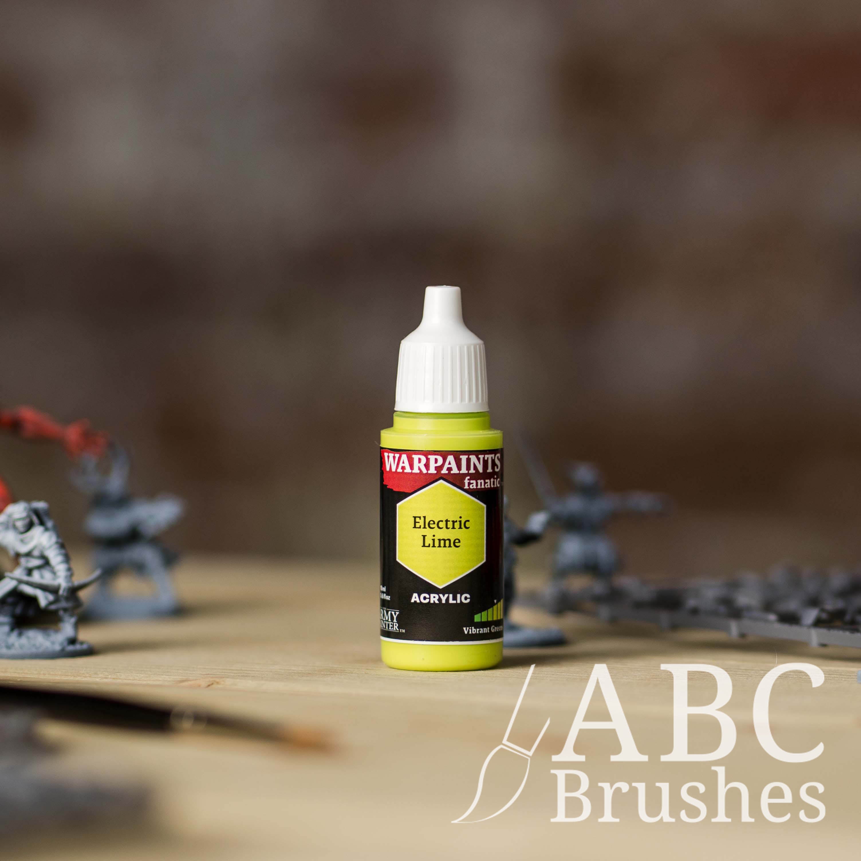 Bottle of the Army Painter Fanatics in the colour Electric Lime with various wargaming models and an ABC paintbrush in the background, on a wooden surface.