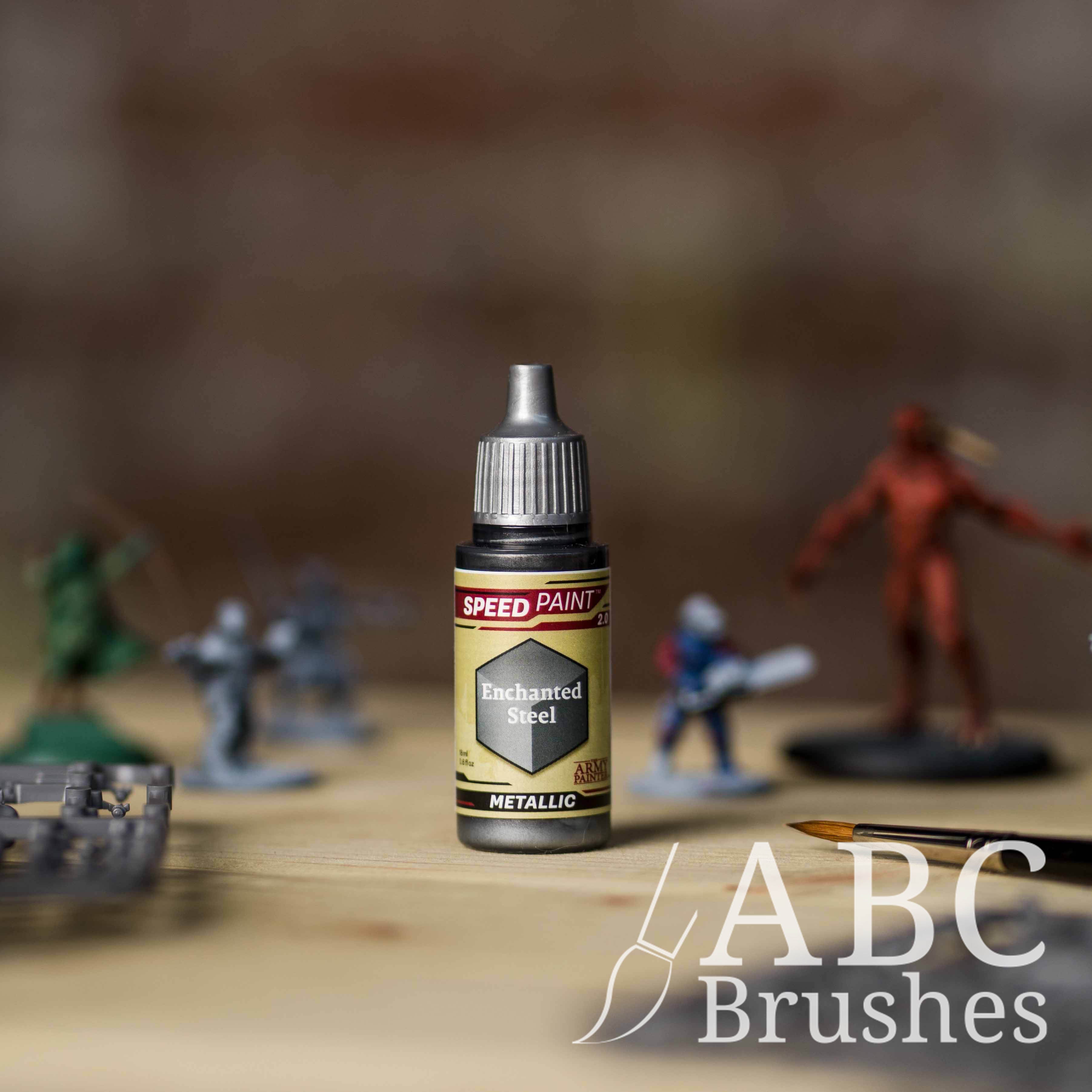 Bottle of the Army Painters Metallic Speedpaint in the colour Enchanted Steel, with wargaming models and an ABC paintbrush in the background, on a wooden surface.