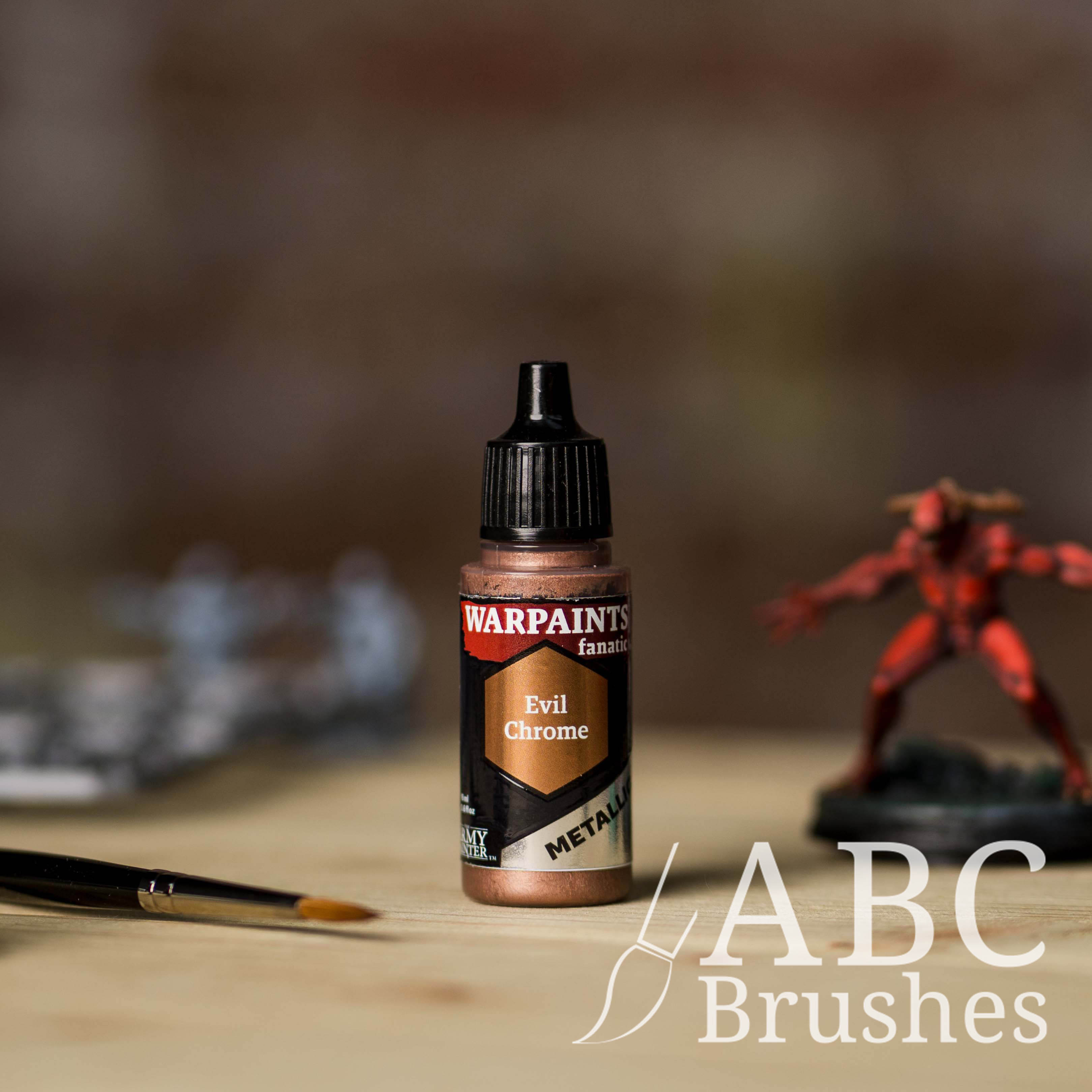 Bottle of the Army Painter Fanatics Metallic paint in the colour Evil Chrome with various wargaming models and an ABC paintbrush in the background, on a wooden surface.