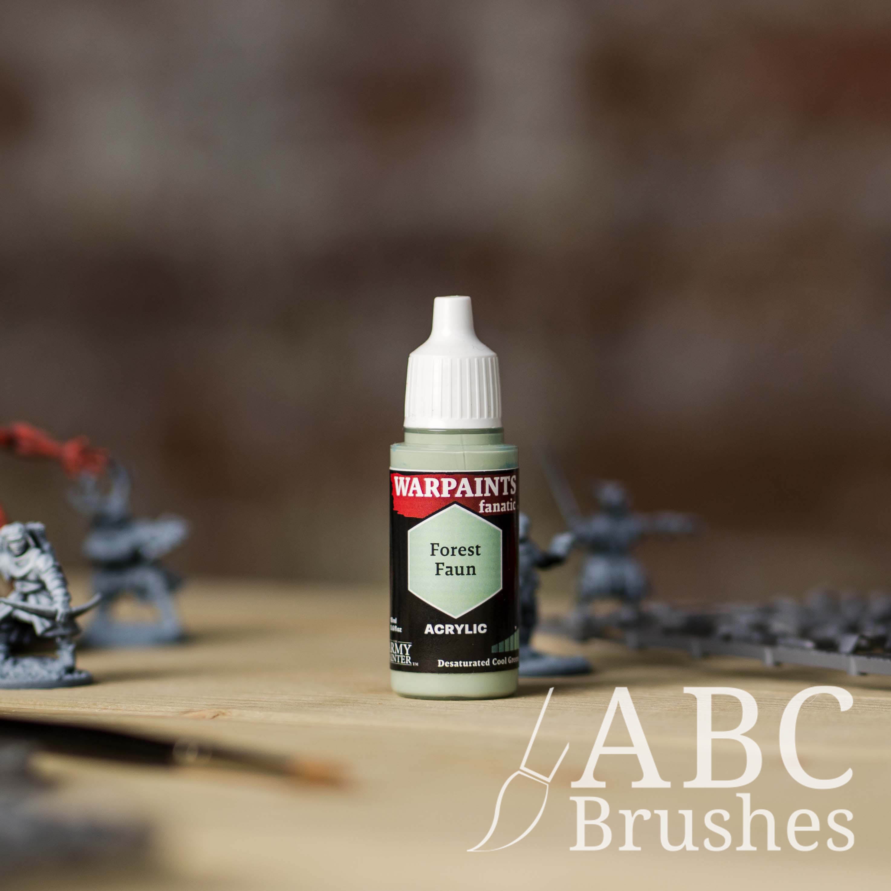 Bottle of the Army Painter Fanatics in the colour Forest Faun with various wargaming models and an ABC paintbrush in the background, on a wooden surface.