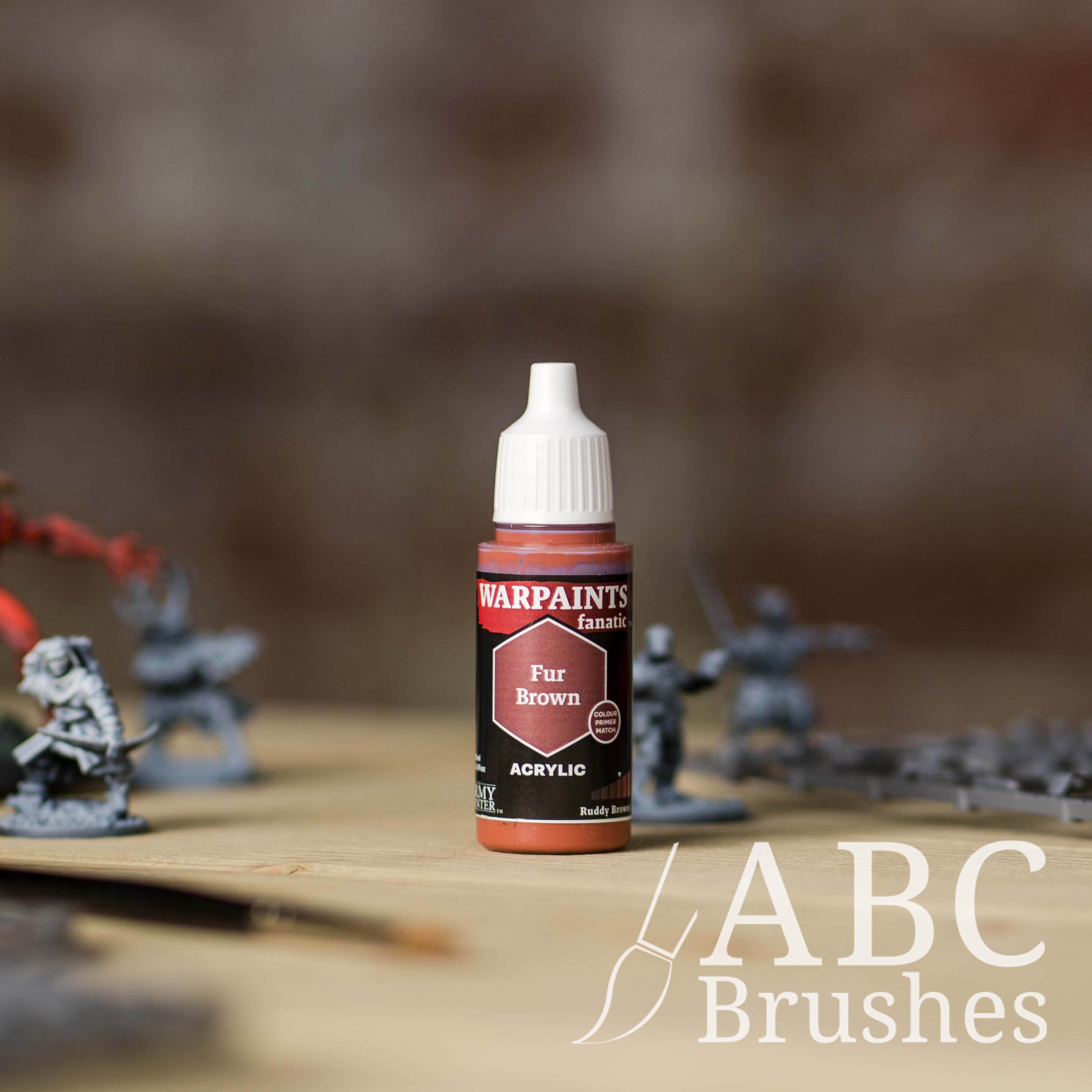 Bottle of the Army Painter Fanatics in the colour Fur Brown with various wargaming models and an ABC paintbrush in the background, on a wooden surface.