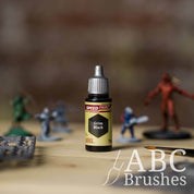 Bottle of the Army Painters Speedpaint in the colour Grim Black, with wargaming models and an ABC paintbrush in the background, on a wooden surface.