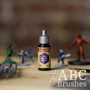 Bottle of the Army Painters Speedpaint in the colour Hive Dweller Purple, with wargaming models and an ABC paintbrush in the background, on a wooden surface.