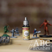 Bottle of the Army Painters Speedpaint in the colour Holy White, with wargaming models and an ABC paintbrush in the background, on a wooden surface.