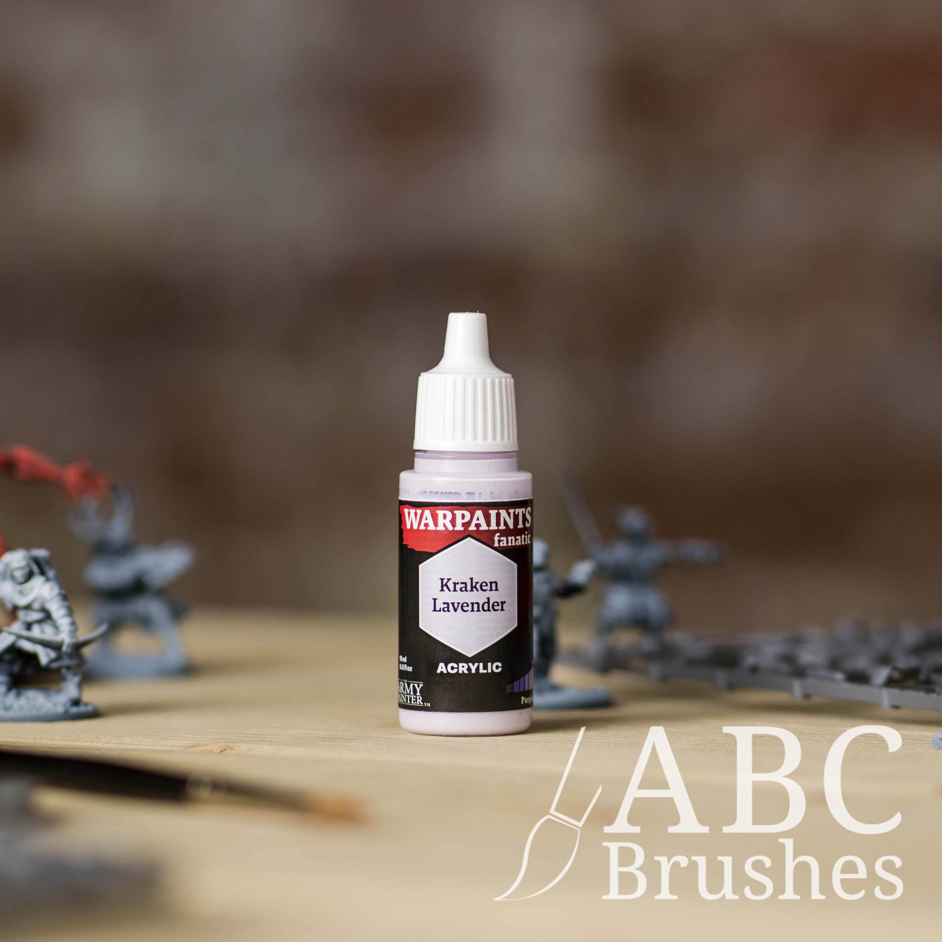 Bottle of the Army Painter Fanatics in the colour Kraken Lavender with various wargaming models and an ABC paintbrush in the background, on a wooden surface.