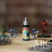 Bottle of the Army Painters Speedpaint in the colour Lizardfolk Cyan, with wargaming models and an ABC paintbrush in the background, on a wooden surface.