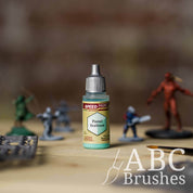 Bottle of the Army Painters Speedpaint in the colour Pastel Seafoam, with various wargaming models and an ABC paintbrush in the background, on a wooden surface.