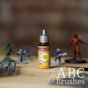 Bottle of the Army Painters Speedpaint in the colour Pastel Yellow, with wargaming models and an ABC paintbrush in the background, on a wooden surface.