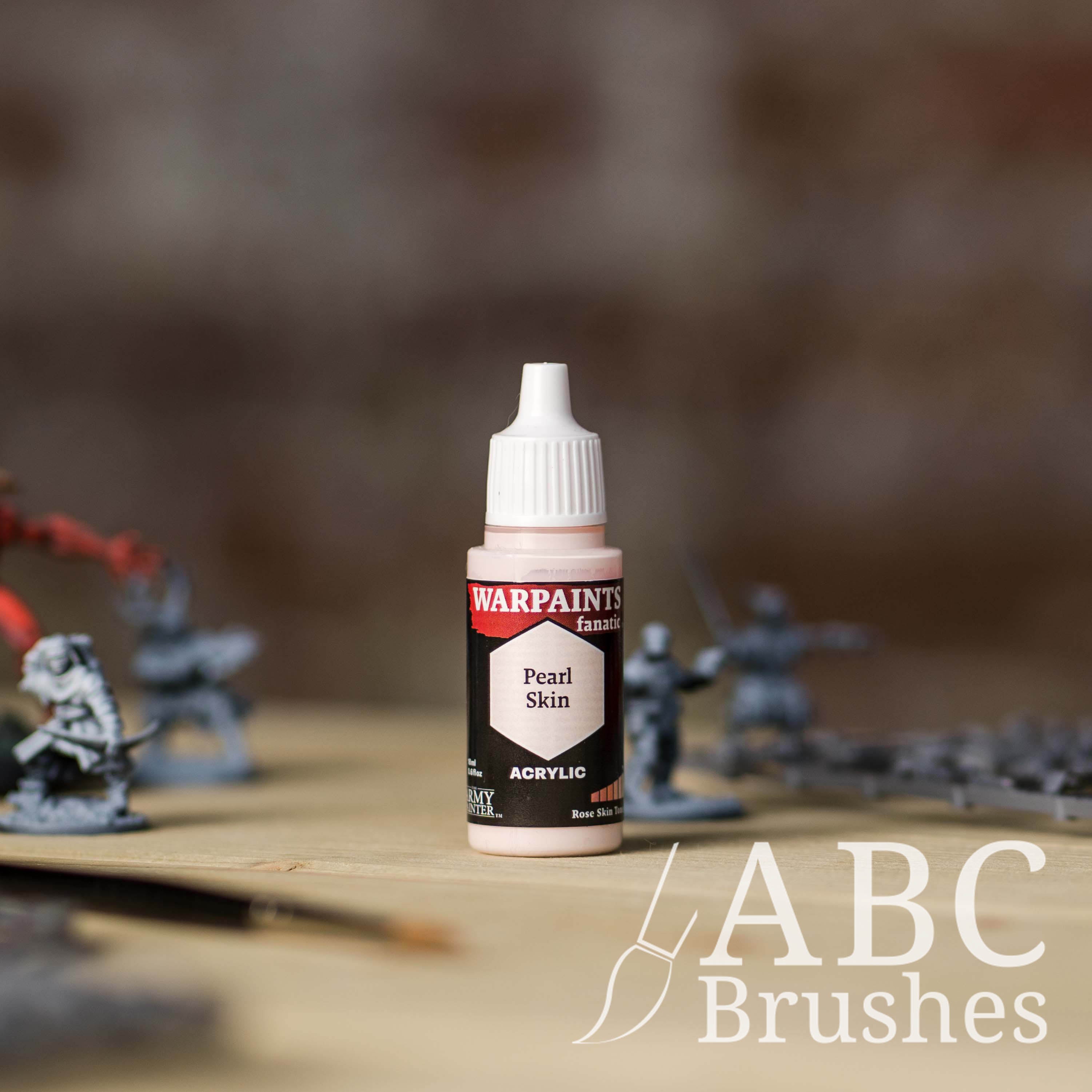 Bottle of the Army Painter Fanatics in the colour Pearl Skin with various wargaming models and an ABC paintbrush in the background, on a wooden surface.
