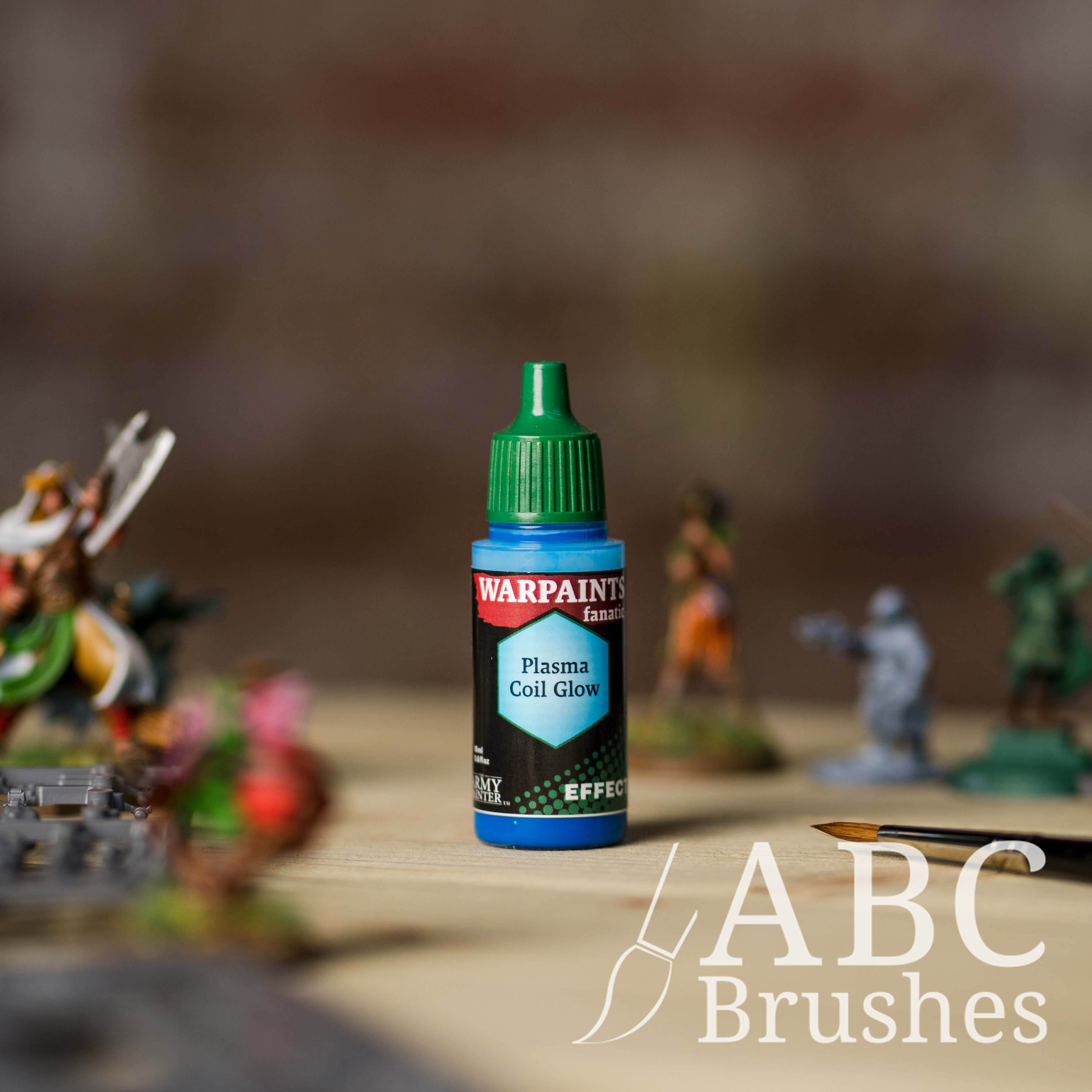Bottle of the Army Painter Fanatics Effects in the colour Plasma Coil Glow with various wargaming models and an ABC paintbrush in the background, on a wooden surface.
