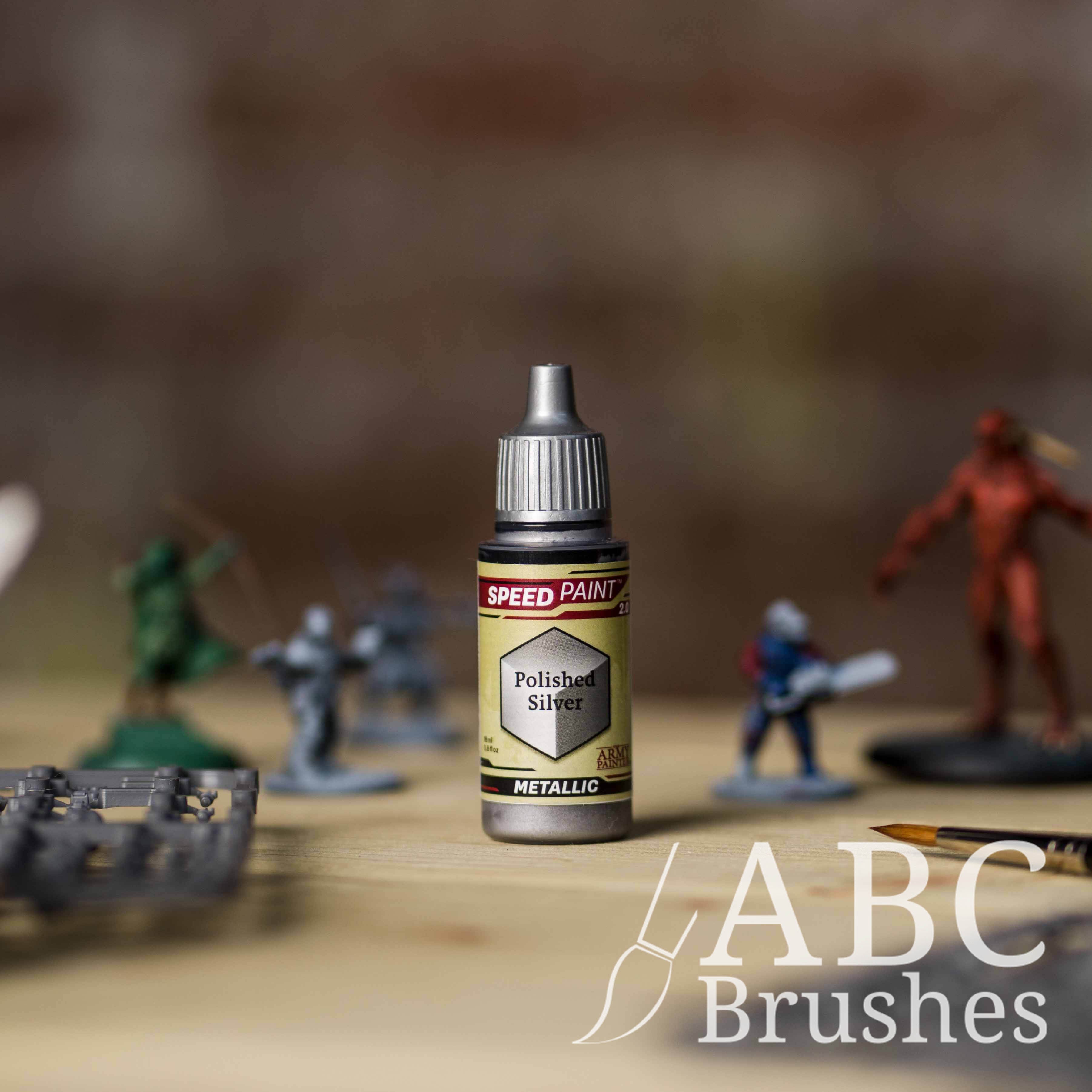 Bottle of the Army Painters Metallic Speedpaint in the colour Polished Silver, with wargaming models and an ABC paintbrush in the background, on a wooden surface.