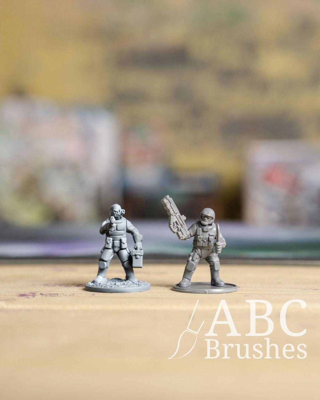 Two mini figures stood next to each other, one primed on the left and the other un-primed.  