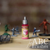 Bottle of the Army Painters Speedpaint in the colour Princess Pink, with wargaming models and an ABC paintbrush in the background, on a wooden surface.