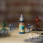 Bottle of the Army Painters Speedpaint in the colour Raging Sea, with wargaming models and an ABC paintbrush in the background, on a wooden surface.