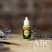 Bottle of the Army Painter Fanatics in the colour Rainforest with various wargaming models and an ABC paintbrush in the background, on a wooden surface.